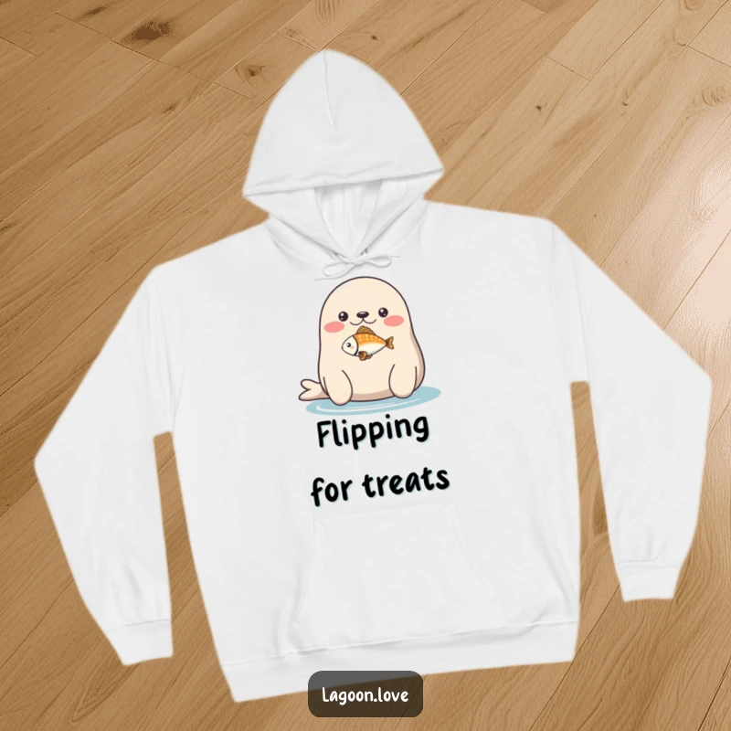 Funny hoodie: a plump, round seal with a delightful expression balancing a tiny, multicolored fish on its nose.